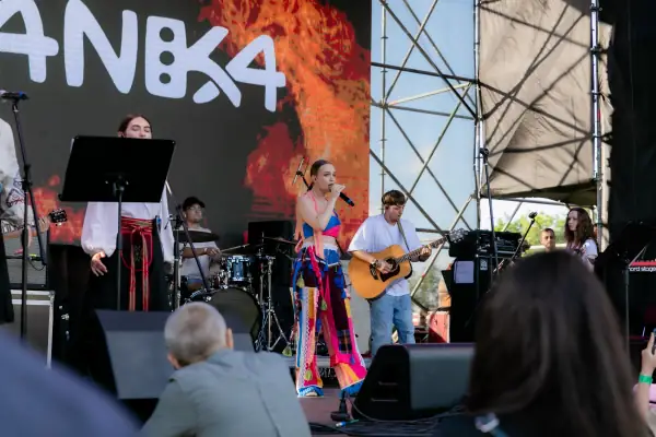 Співачка у яскравому сценічному костюмі виступає з музикантами на фестивальній сцені.